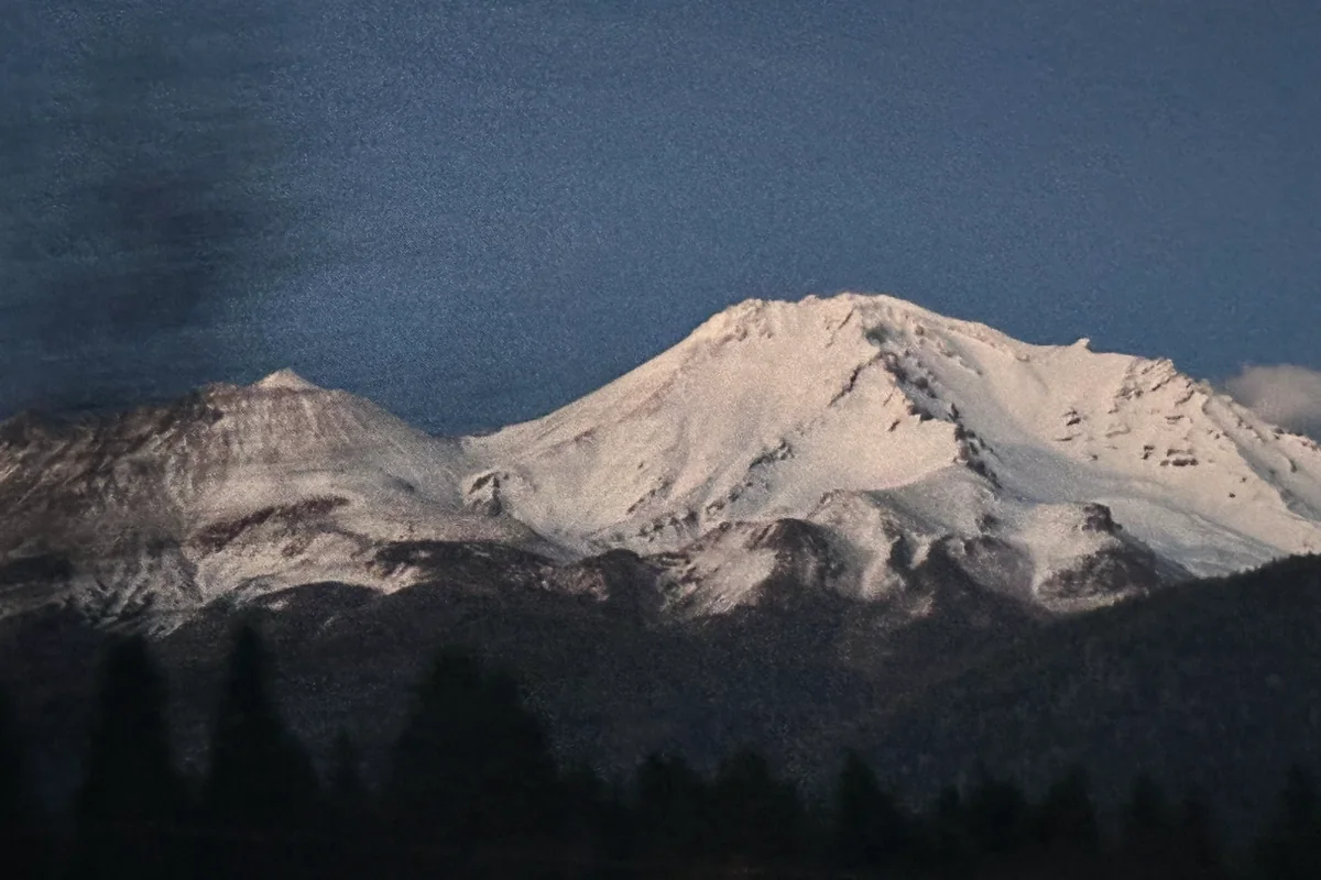 A snow-covered mountain lit pink at dusk
