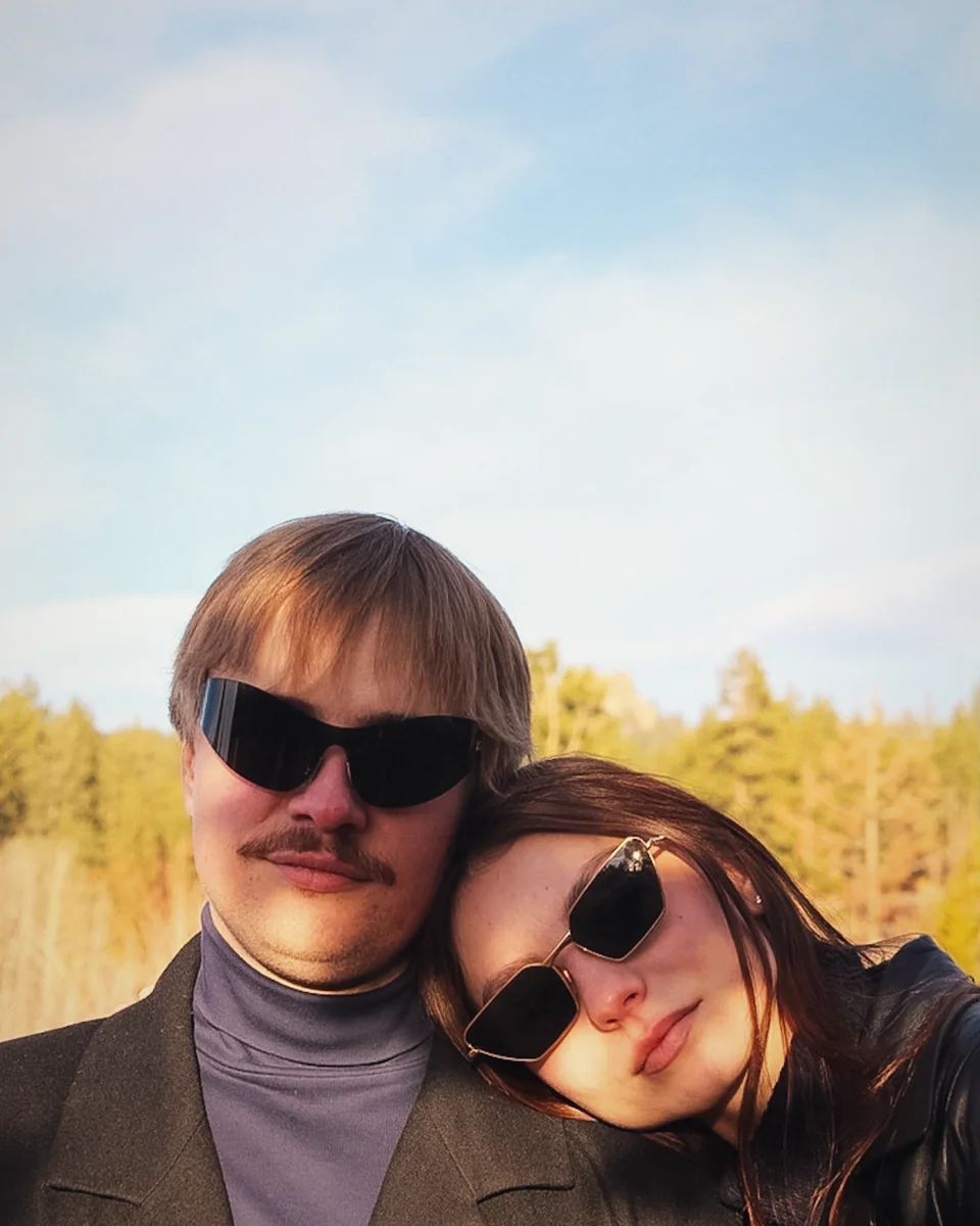 Close selfie of a couple in sunglasses against golden pines
