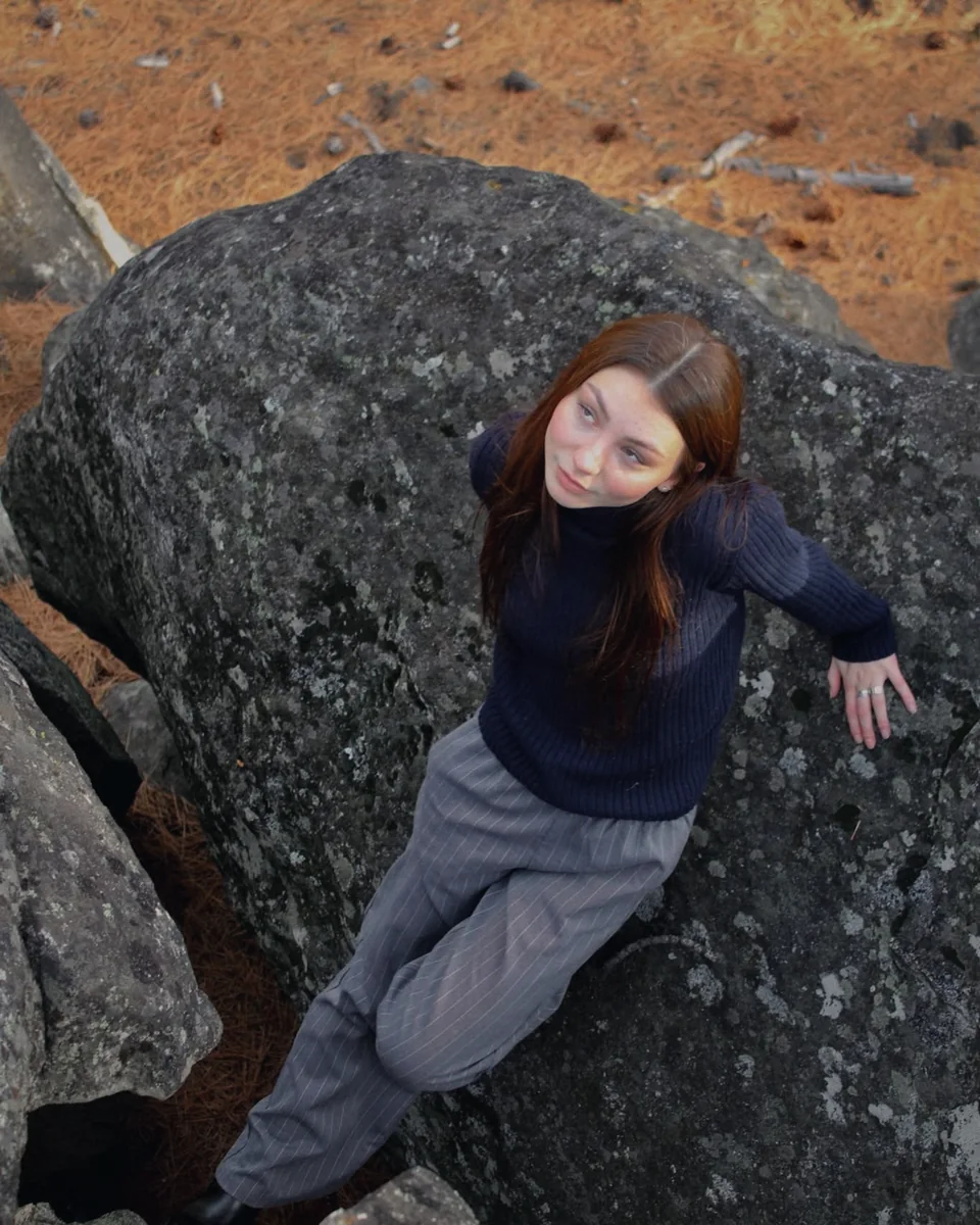 A woman reclining on a large granite boulder, seen from above