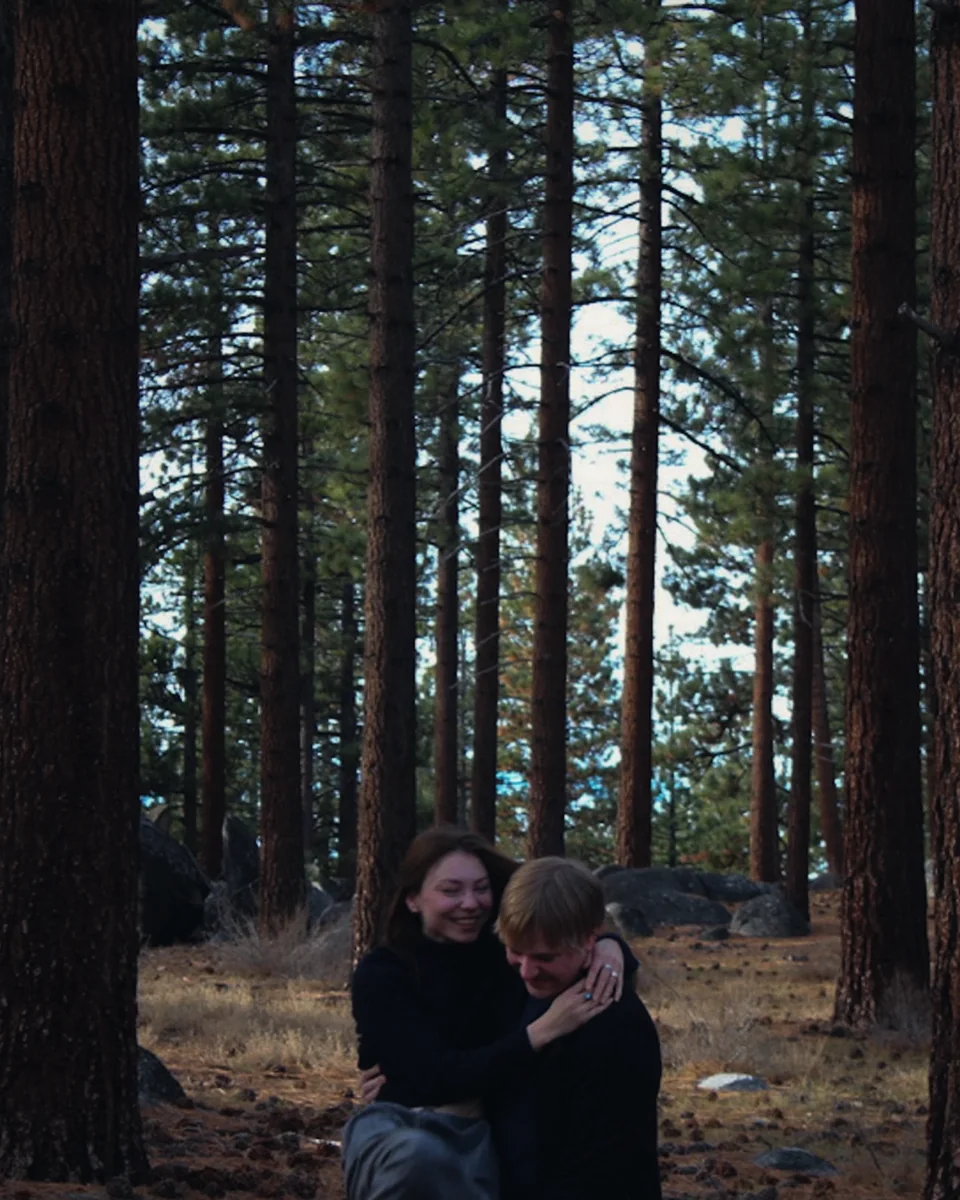 A couple hugging in a pine forest