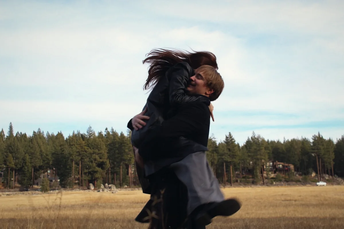 A couple spinning in an embrace in an open meadow